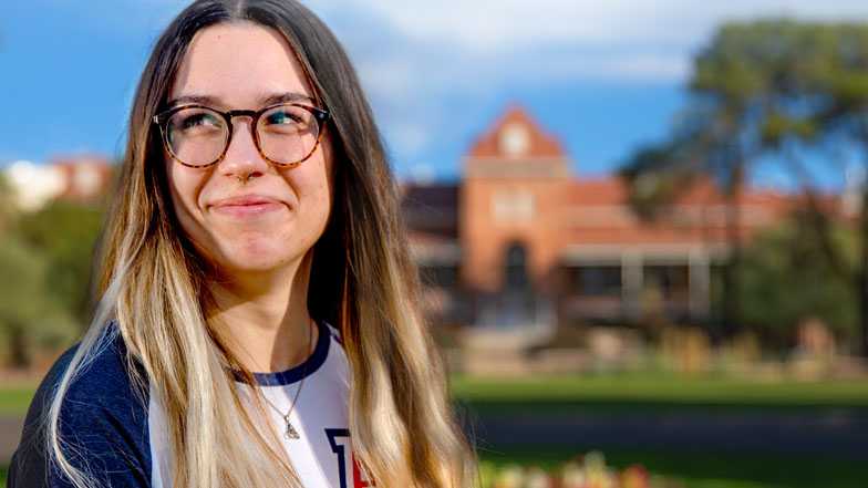 UArizona student, smiling, in front of Old Main