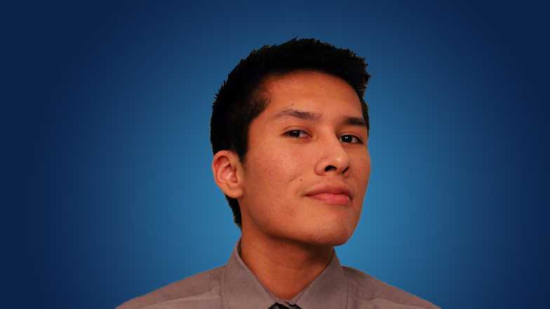 Image of student Justin Billy smiling in front of blue background