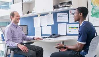 An advisor and student in an office setting, deep in conversation