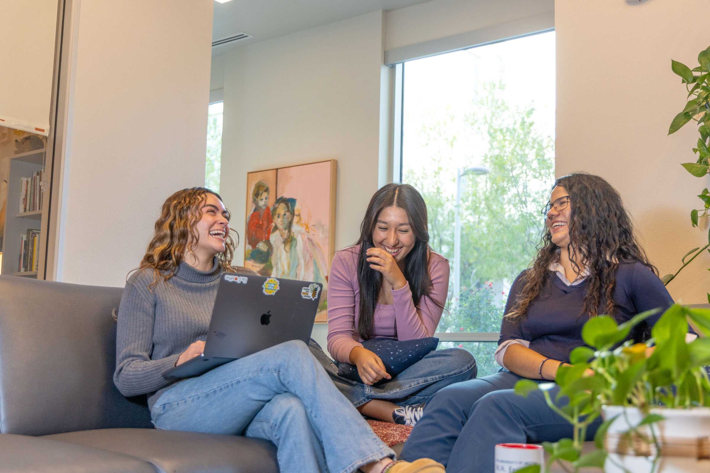 Students laughing and sitting on a couch in the Academic Lounge