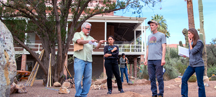Students and professors working together outside of the Old Main building at the University of Arizona.
