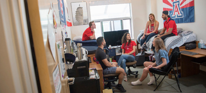 Students hanging out in a campus dorm room talking and enjoying student life.