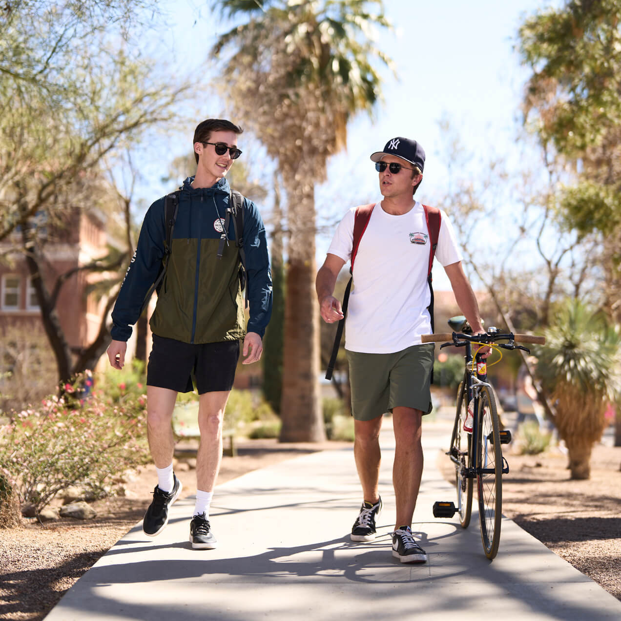 two students walking their bikes on campus