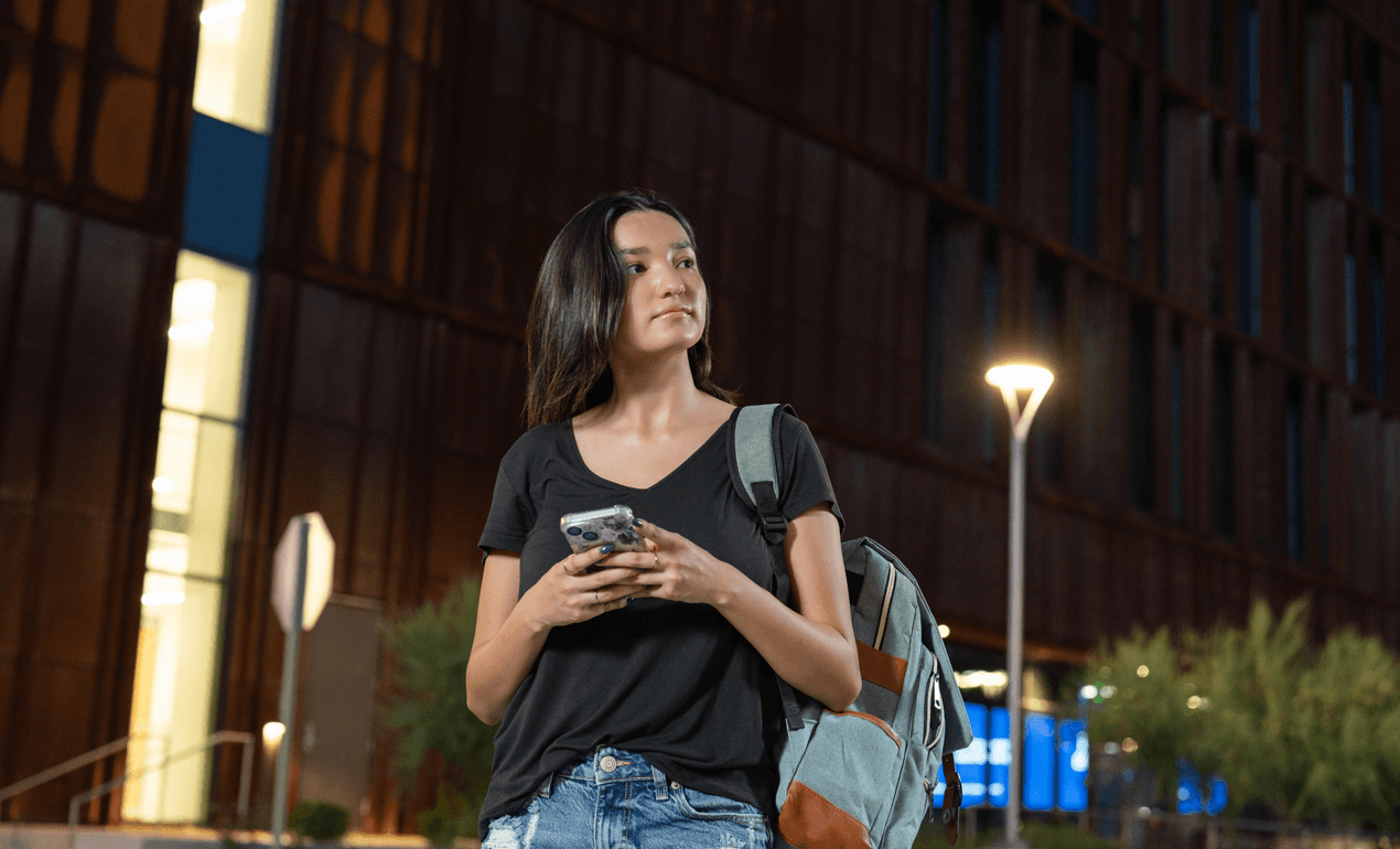 student on cell phone walking around at night