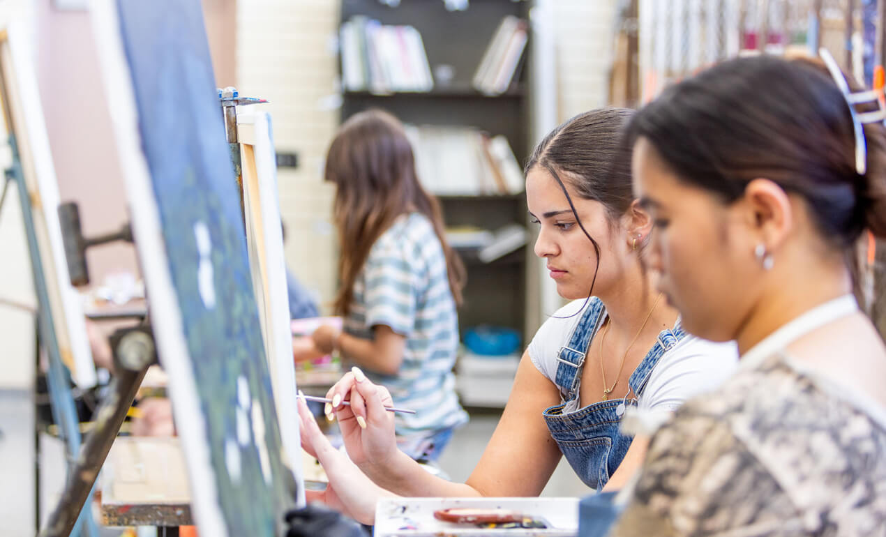 two adults painting together in a class