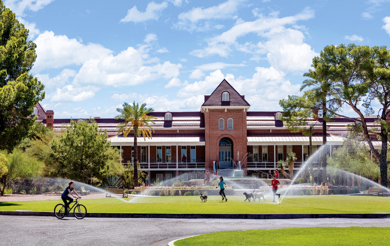 student biking on campus in front of Old Main