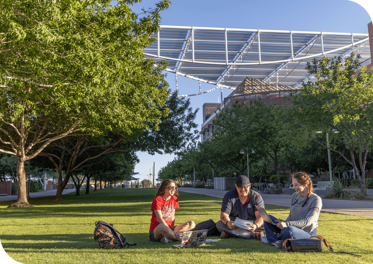three students sitting on the campus grass