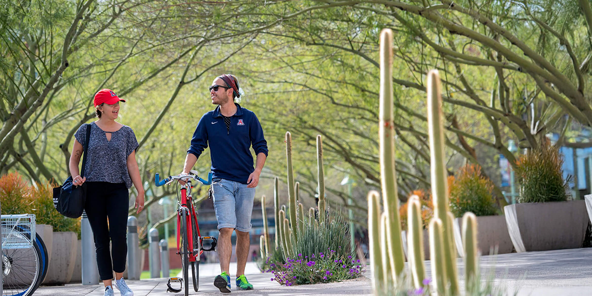 two students walking their bikes on campus