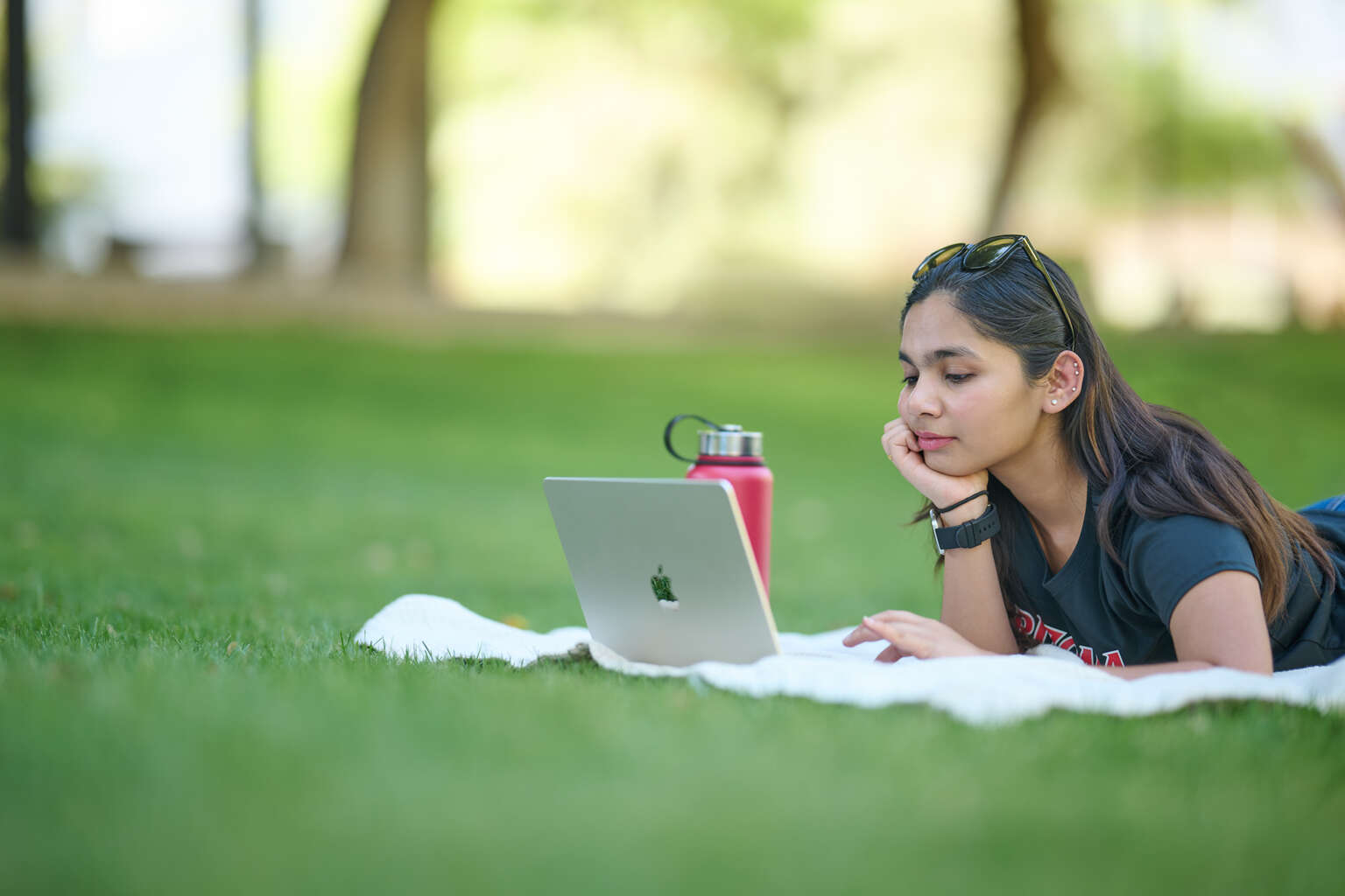student on her laptop on a grass field