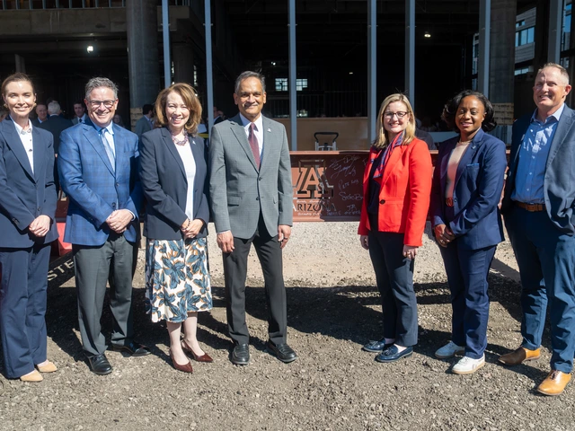people posing for a photo in front of a steel beam on a construction site