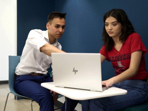 Staff helping a student edit their resume on a laptop