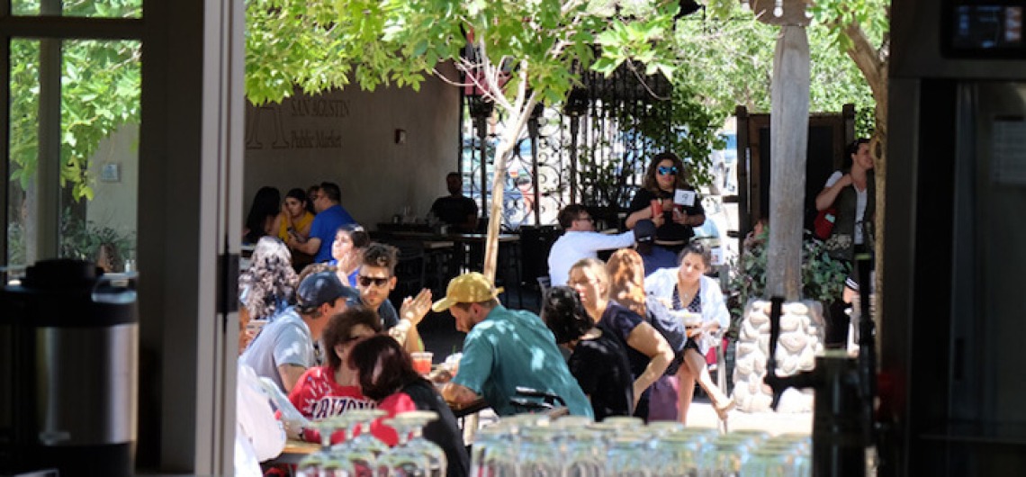 People sitting at outdoor patio on a sunny day at Mercado District in Tucson, Arizona.