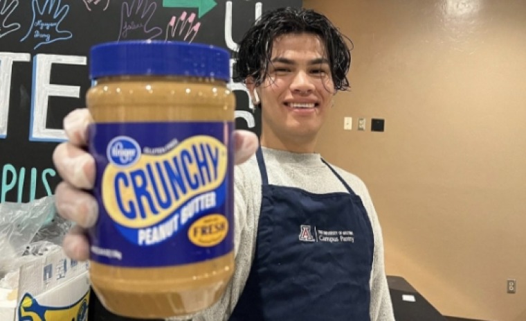 Student at UA Campus Pantry holding a jar of peanut butter