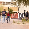 students walking past the U of A main library in front of a large "Bear Down" sign